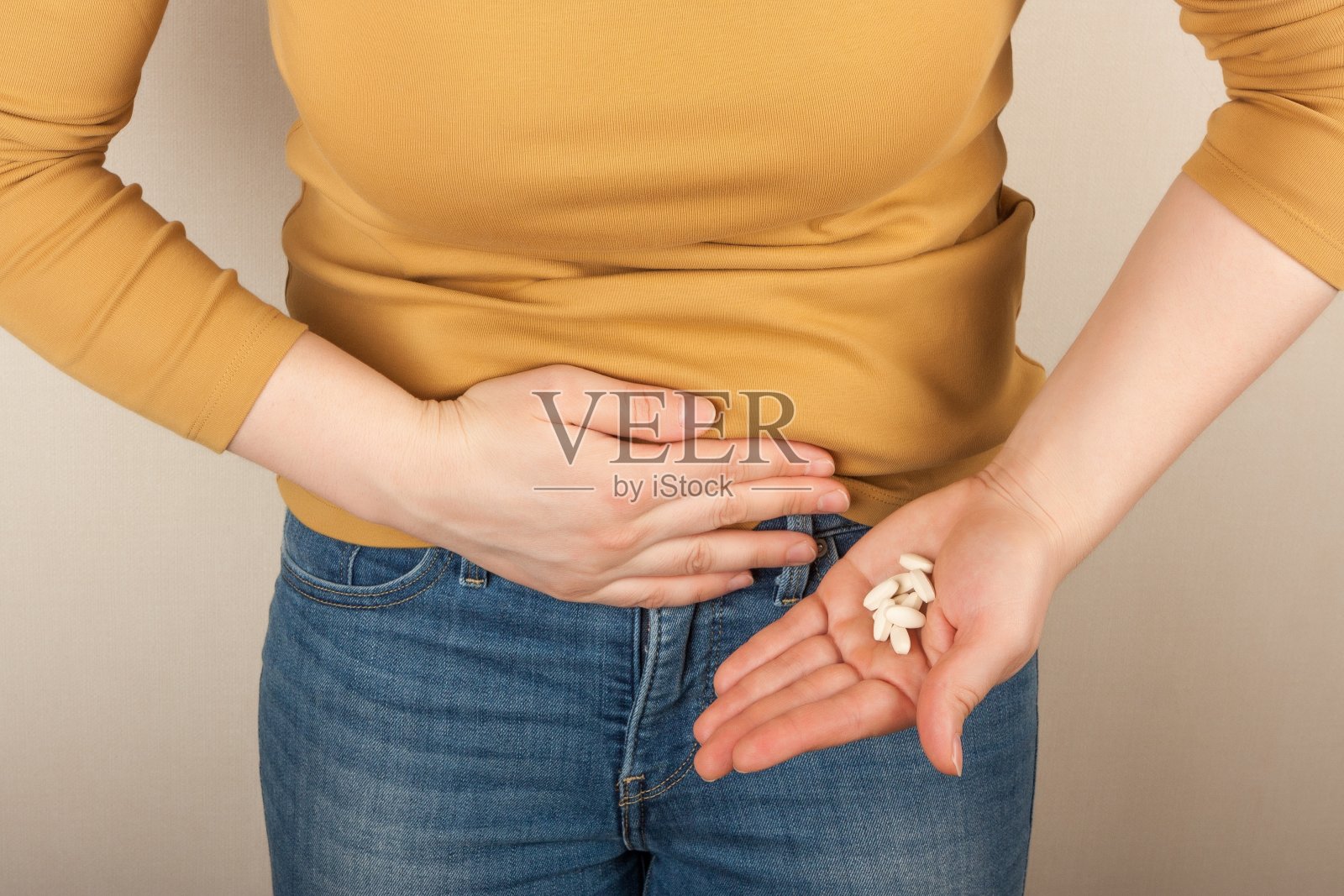 一个手里拿着药，摸着肚子的女人，照片摄影图片