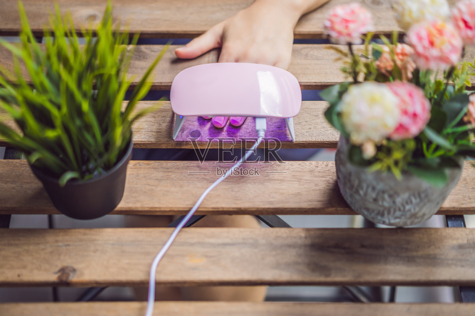 年轻的女士用粉色指甲油和紫外线灯做美甲照片摄影图片