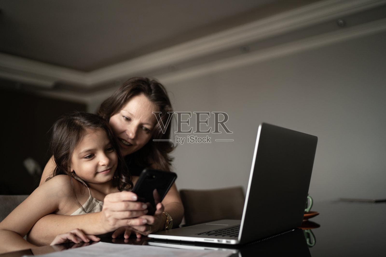 母亲在家工作时，女儿在和她说话照片摄影图片