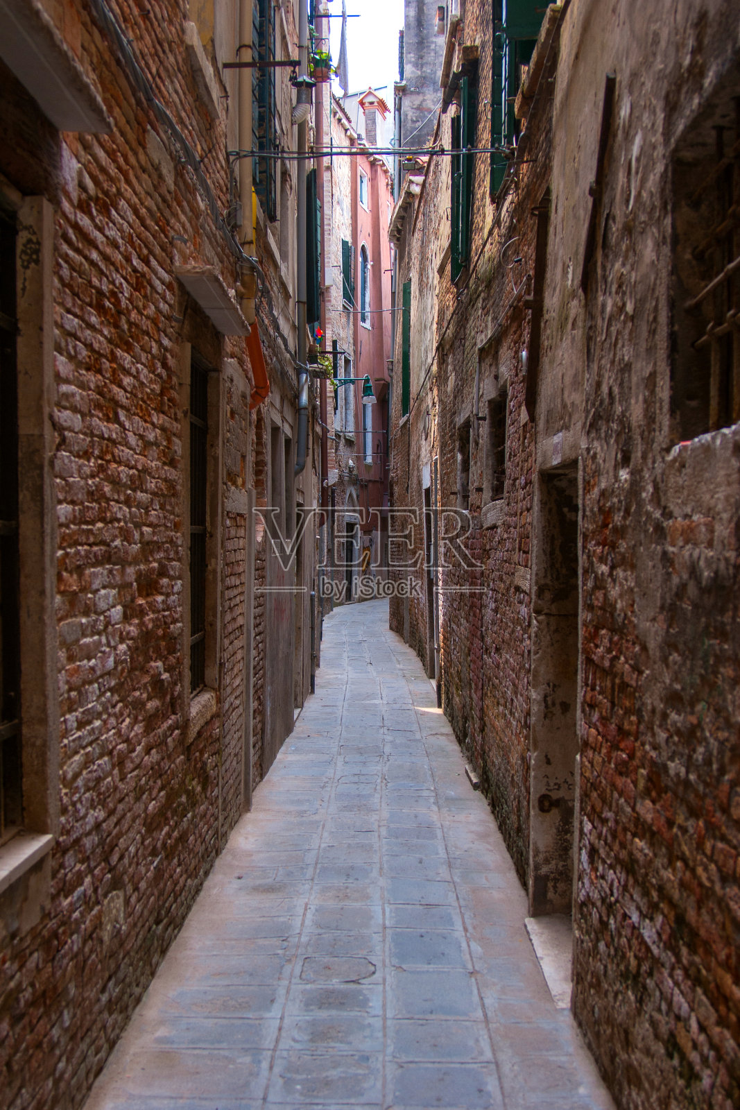这是威尼斯一条狭窄的街道，有老旧的砖房照片摄影图片