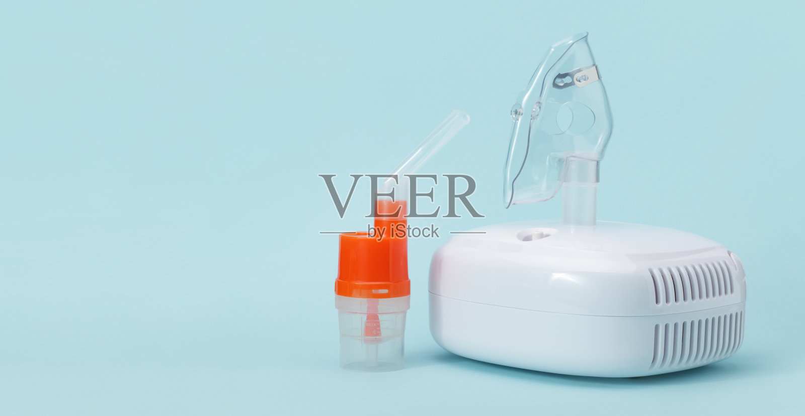 蓝色的呼吸面罩和带喷嘴的雾化杯，用于压缩机吸入器。照片摄影图片