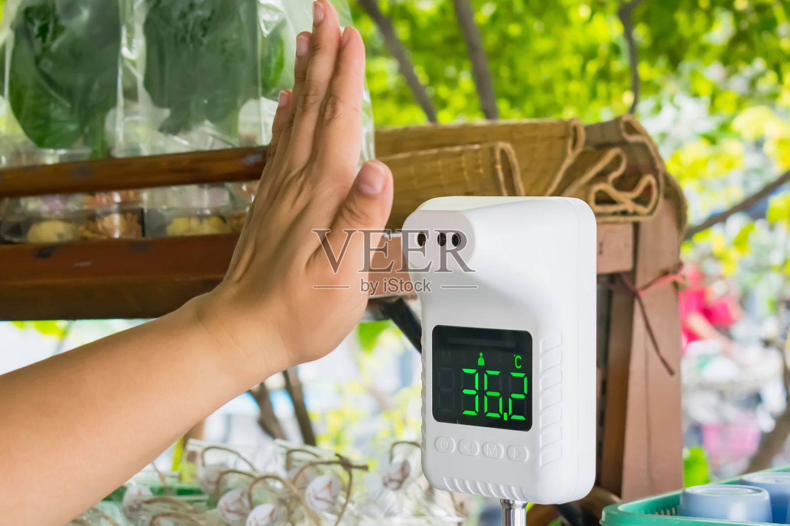 亚洲妇女在进入机构前用红外线温度计检查额头温度，重点关注温度计。冠状病毒筛查19概念。照片摄影图片