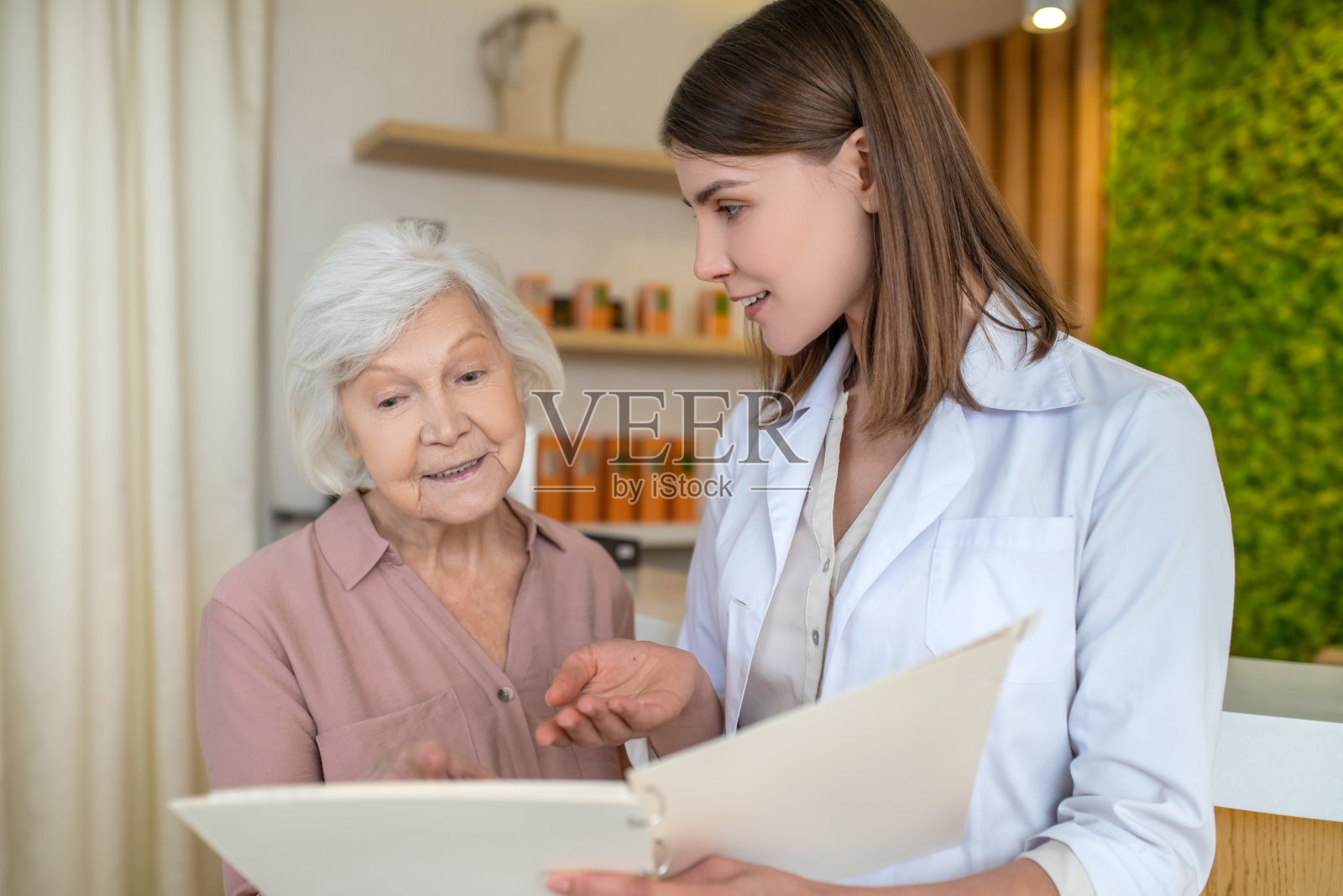 年轻的黑发美容师向顾客展示程序清单照片摄影图片