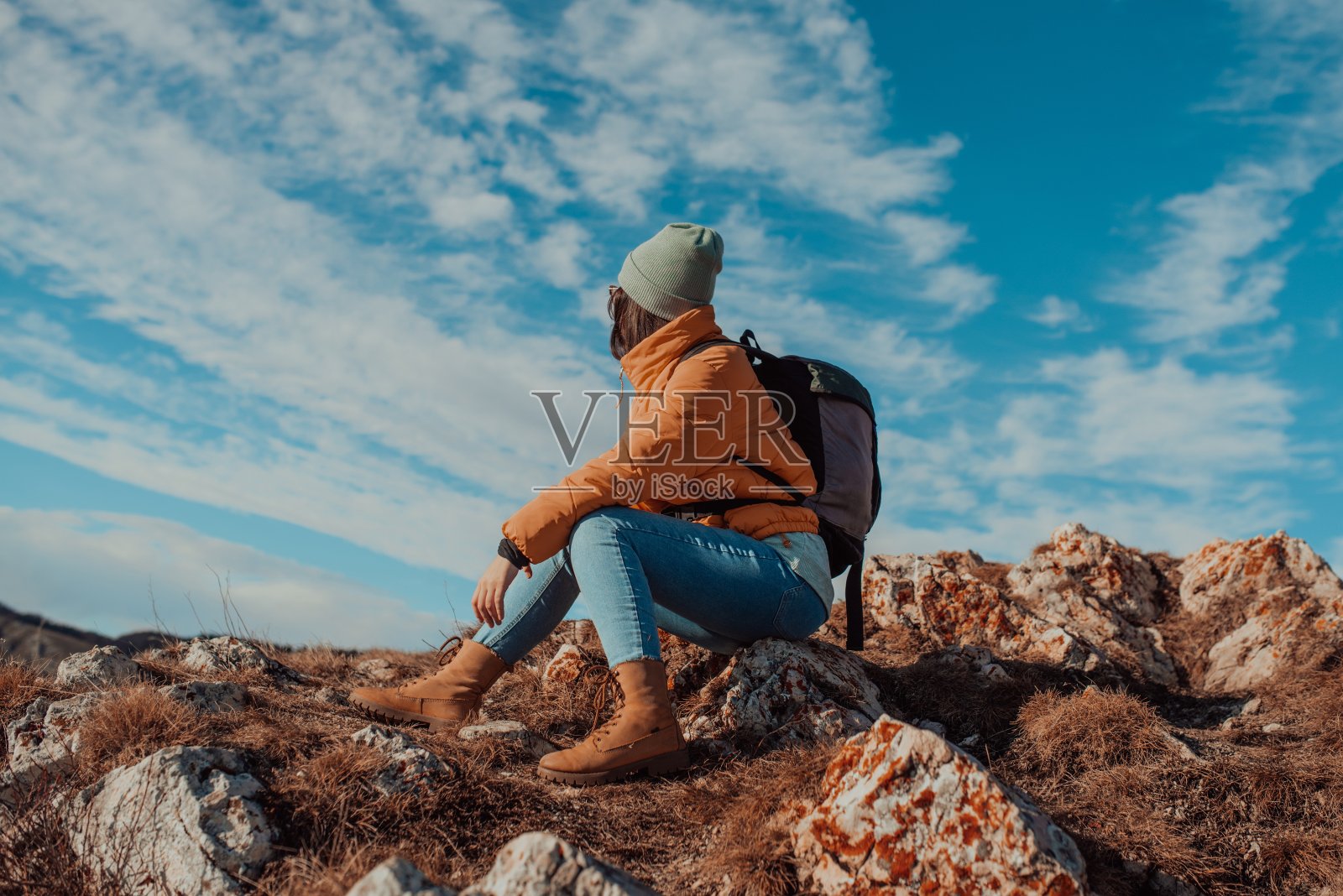 自由旅行者女子坐在山顶上享受大自然的美妙。年轻的女孩在山顶与雪山美景。旅游的概念照片摄影图片