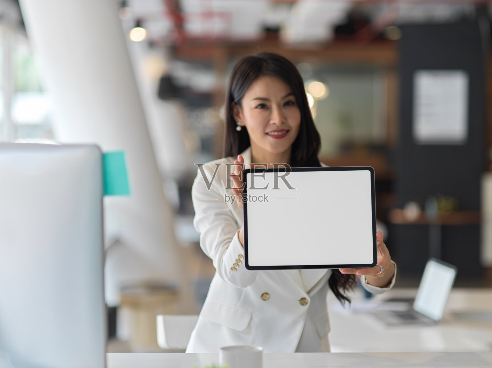 有吸引力的女商人拿着并向相机展示带有模拟屏幕的数码平板电脑照片摄影图片