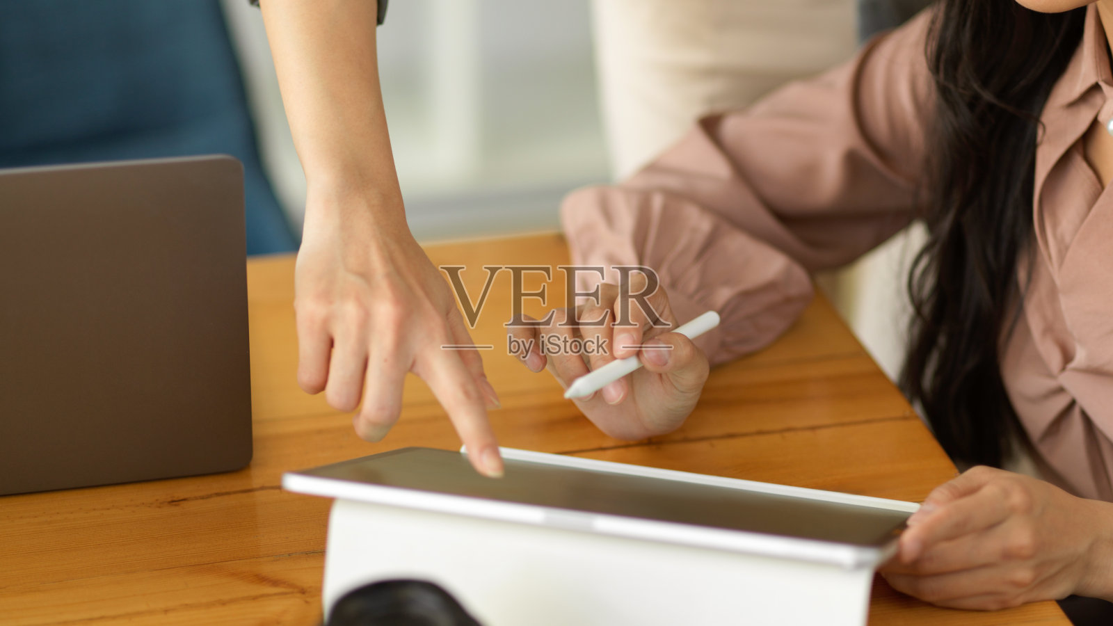 两位女商人一边谈论自己的工作，一边手指着平板电脑的屏幕照片摄影图片