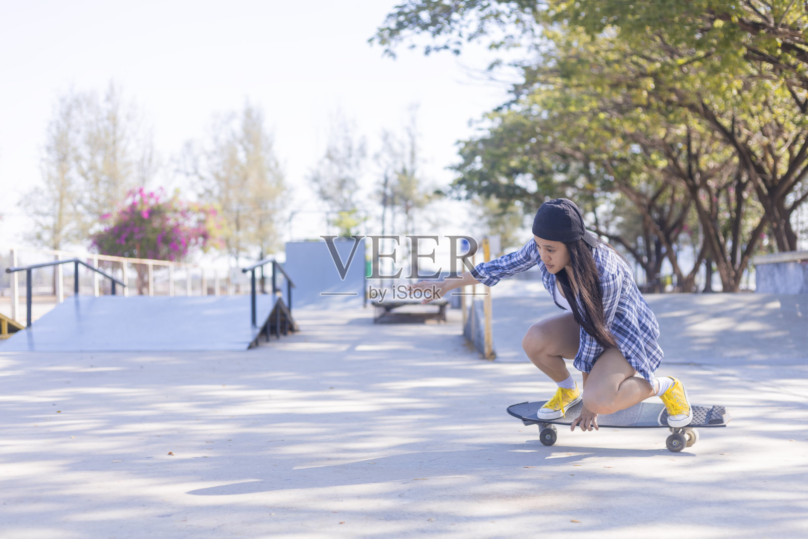 年轻的亚洲妇女在早上在户外滑板公园玩冲浪板。快乐的女人在公园玩冲浪板。运动生活方式概念照片摄影图片