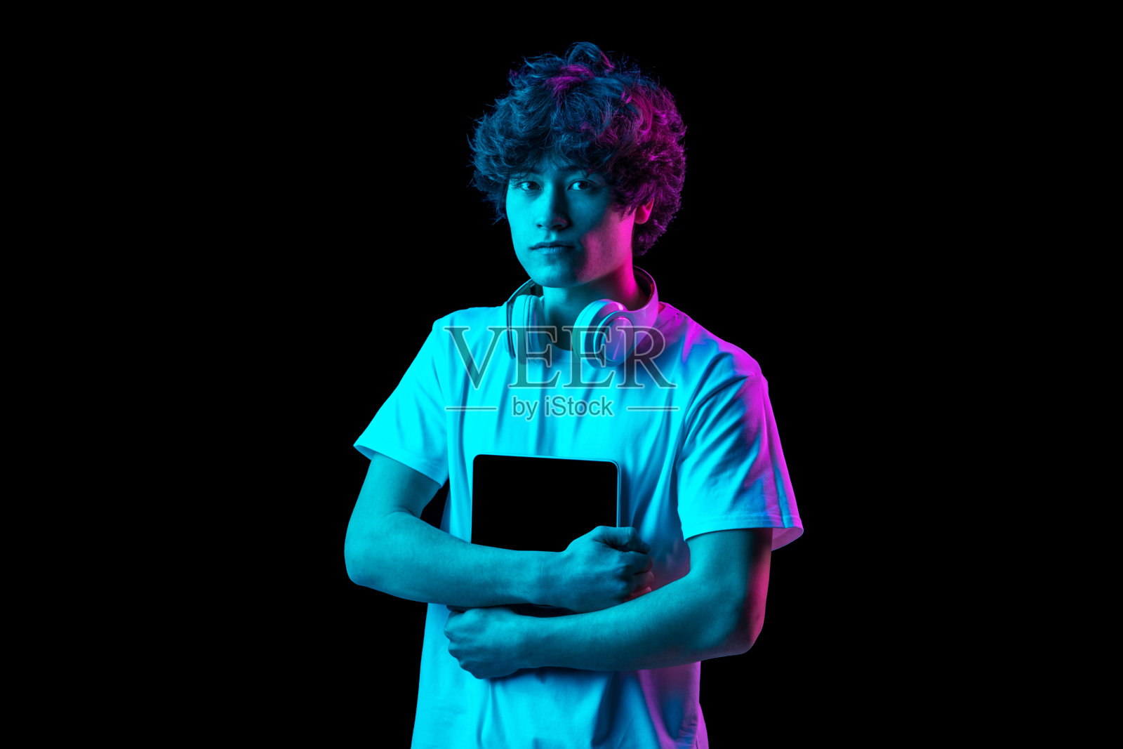 年轻男子的肖像与平板电脑孤立在黑暗背景霓虹灯照片摄影图片