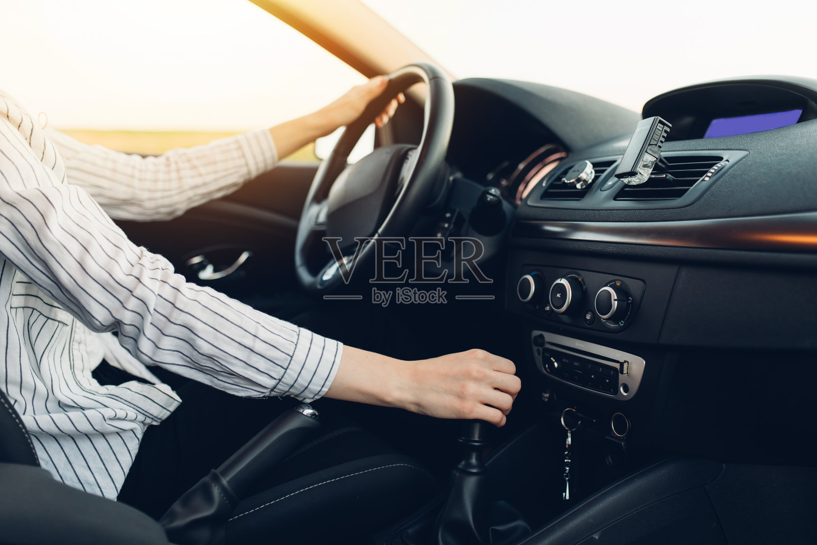 年轻快乐的女人在夕阳下开着她的新车照片摄影图片