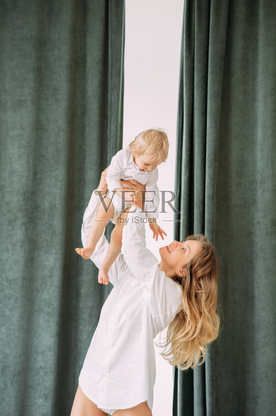 快乐的妈妈和她的小儿子玩。照片摄影图片