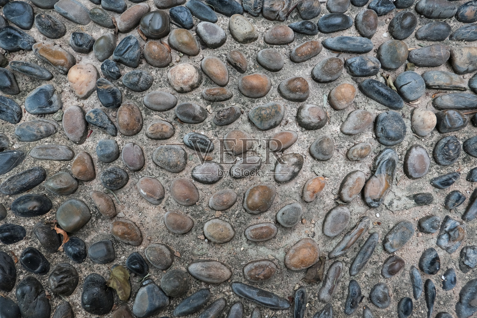 石墙的背景特写。纹理大小不一的彩石在混凝土中。用许多石头砌成的粗糙的旧混凝土墙照片摄影图片