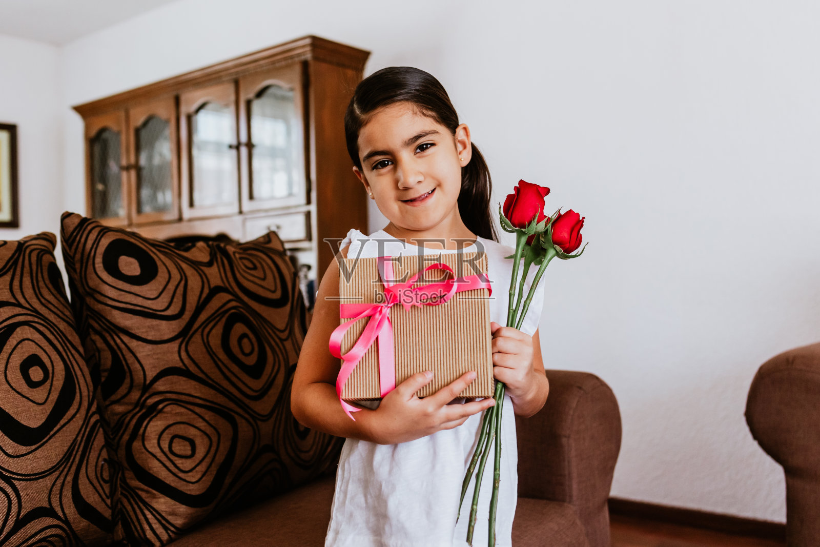 墨西哥城，拉丁小女孩在家里向妈妈祝贺，并送给她鲜花，祝她母亲节快乐照片摄影图片