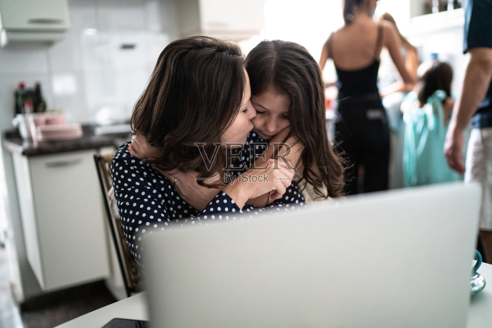 母亲在家工作，女儿拥抱她照片摄影图片
