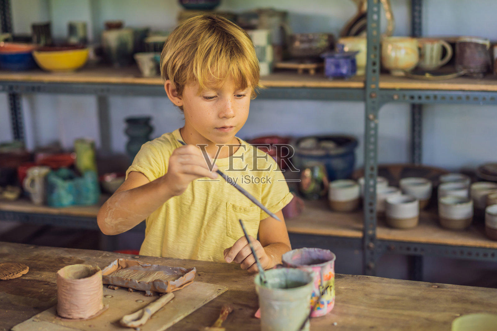 男孩在陶艺坊做陶罐照片摄影图片
