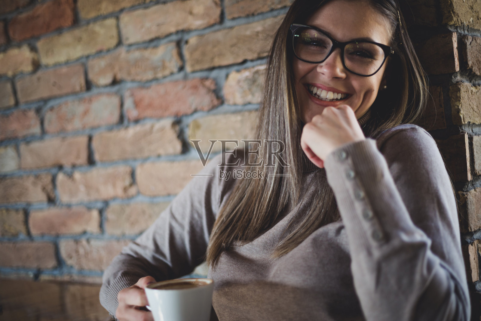 一个面带微笑的戴眼镜的幸福女人，坐在自助餐厅靠墙休息。照片摄影图片