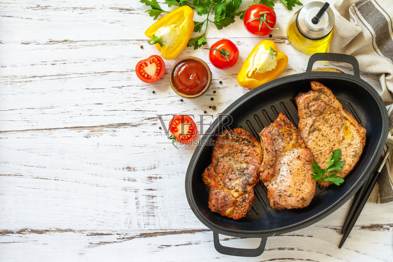 烧烤聚会的菜单。在质朴的木桌上的铸铁平底锅里放上带骨的烤猪肉和香料。俯视图平铺。副本的空间。照片摄影图片