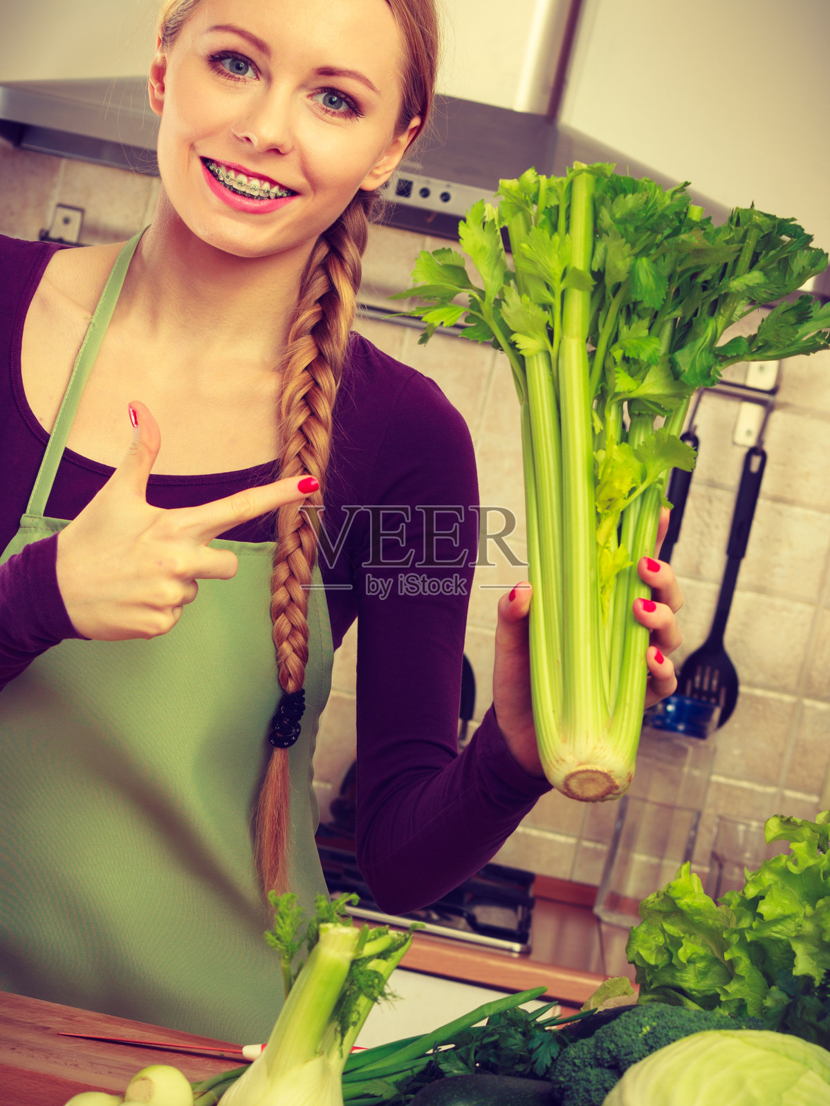 厨房里的女人拿着绿色芹菜照片摄影图片