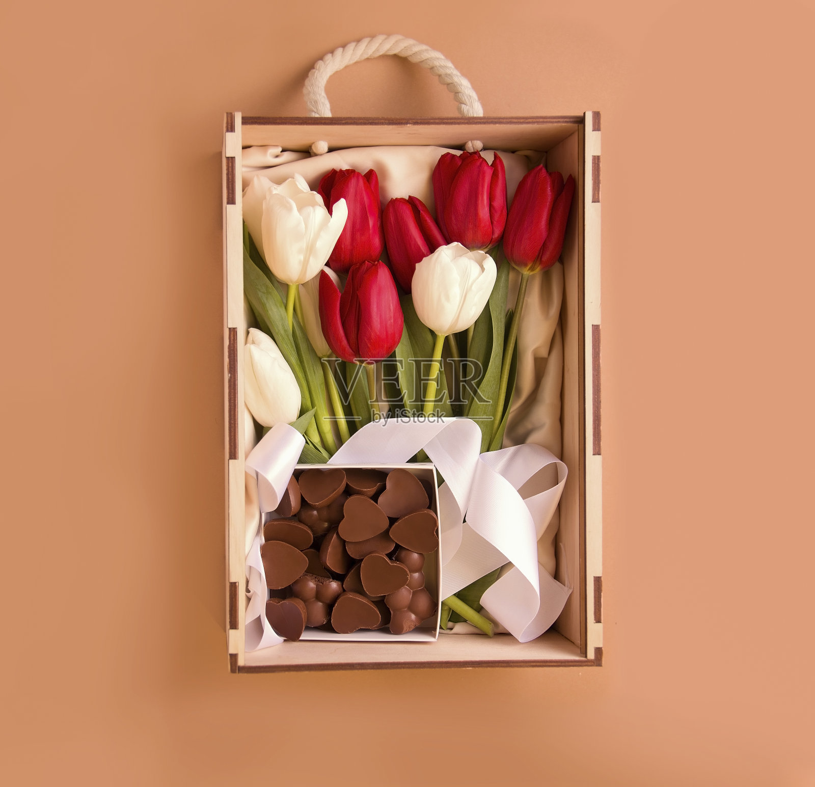 节日的礼物。棕色背景上有鲜花和巧克力的盒子。从上面的观点照片摄影图片