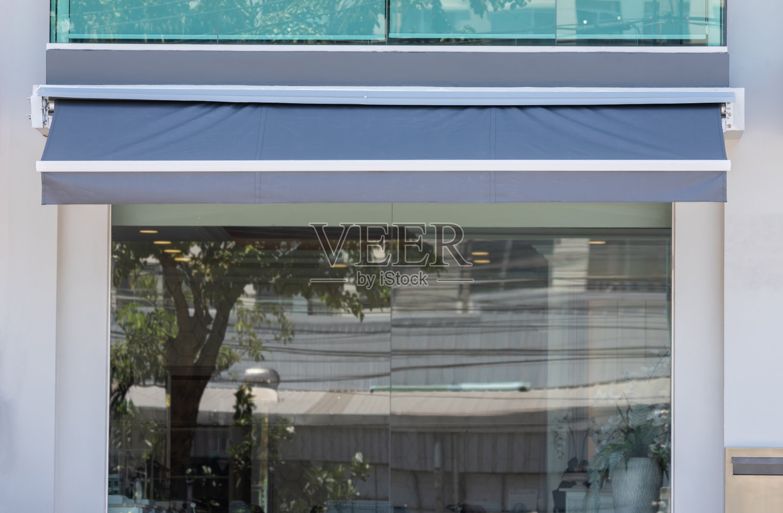 商店玻璃窗上的蓝色遮阳篷。照片摄影图片