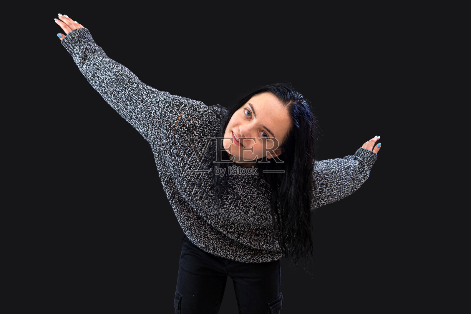 一位穿着灰色毛衣的长发女子在黑色背景下用手势示意照片摄影图片