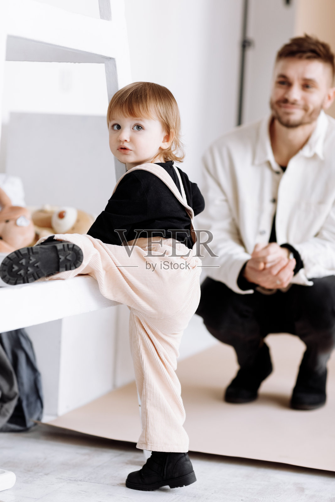 时尚的男人正在玩可爱的孩子宝贝女孩在装饰工作室。父女关系。爱、亲子、童年的概念。父亲节，爱心关怀，深情奉献温馨亲情照片摄影图片