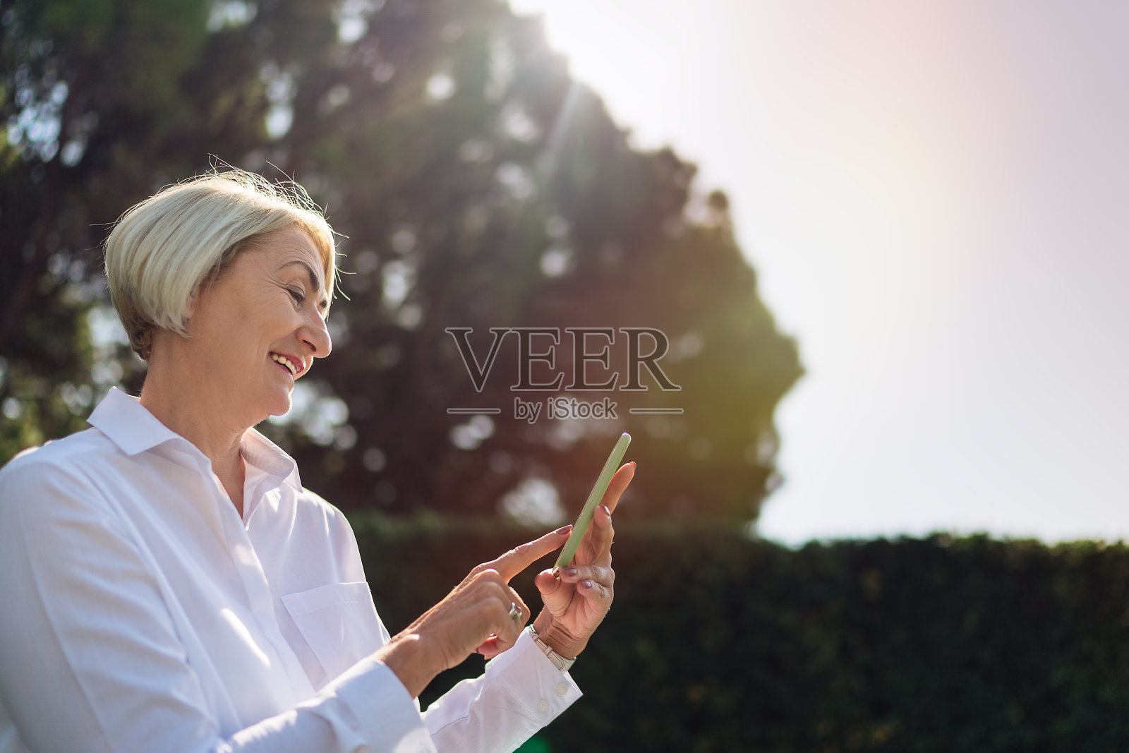 一名女子在公园休息时使用手机照片摄影图片
