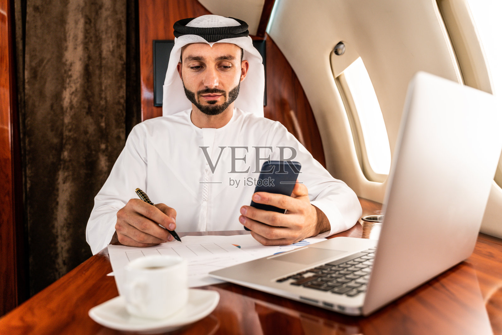 穿着坎多拉长袍乘坐私人飞机的阿拉伯男子照片摄影图片