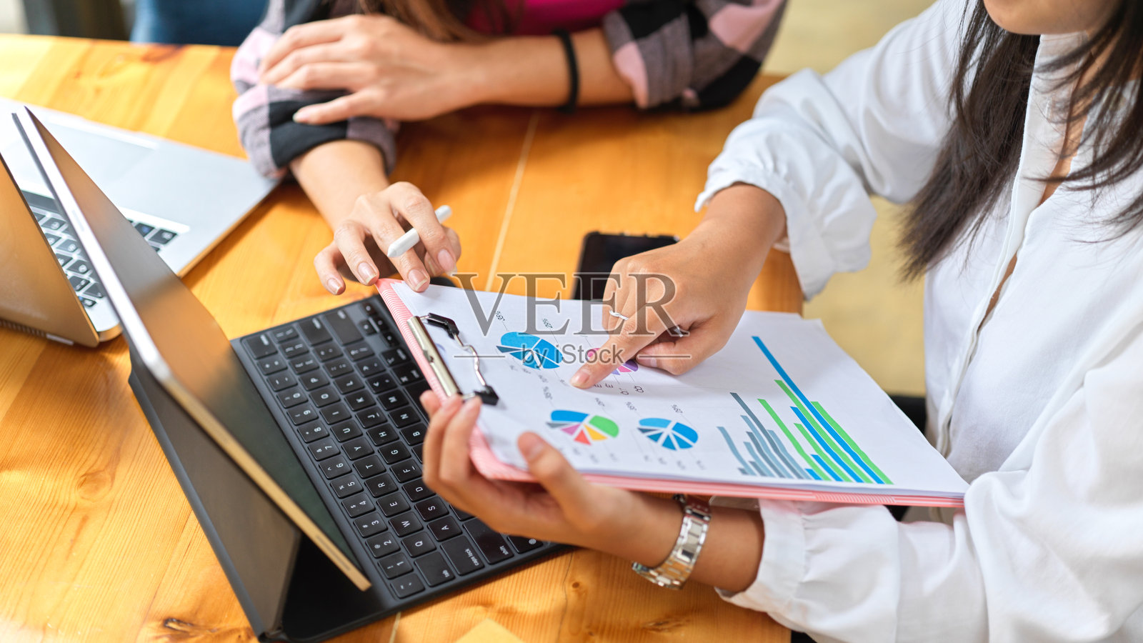 两个女学生在图书馆用文件和笔记本电脑咨询他们的小组作业照片摄影图片