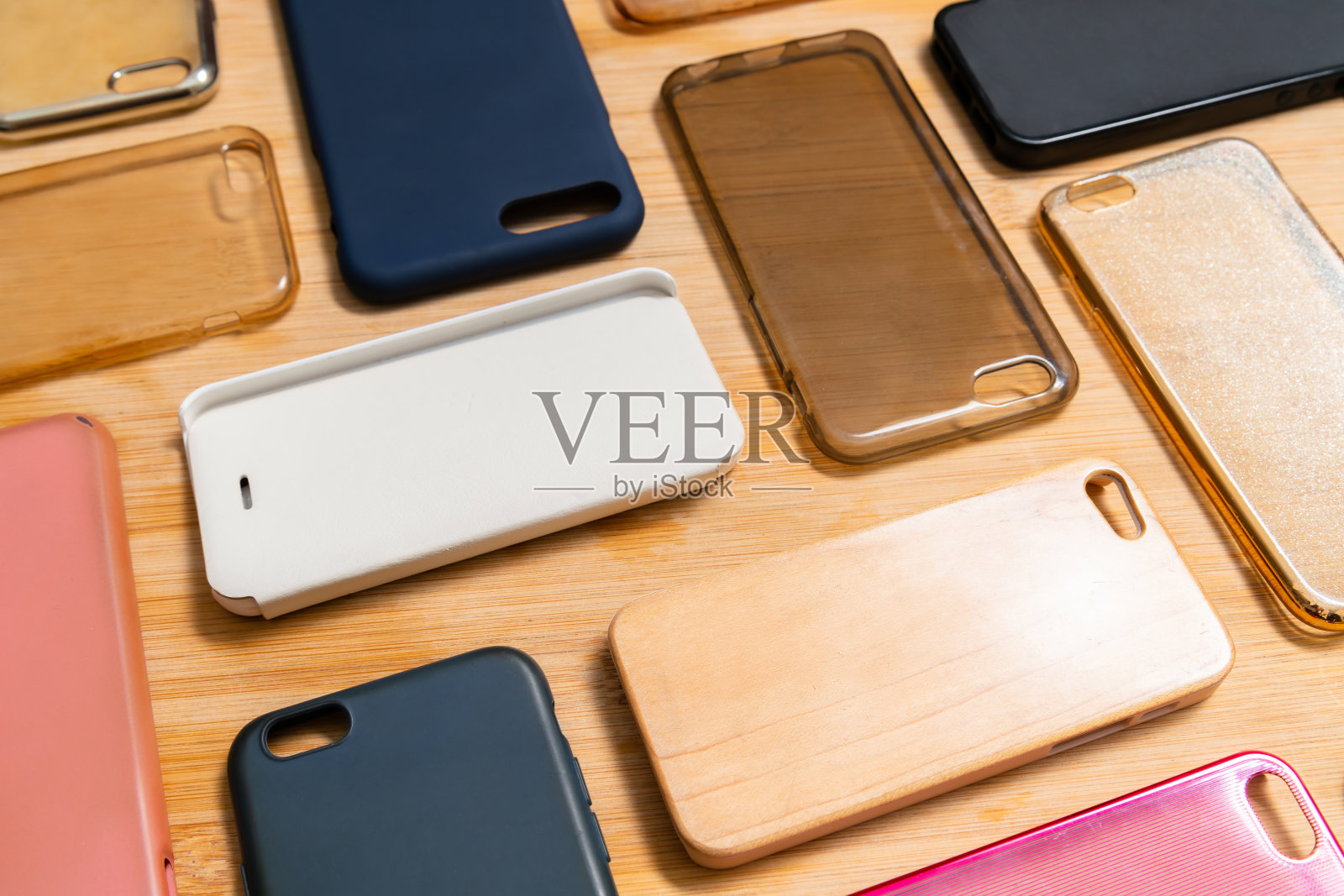 一堆彩色塑料手机后盖。选择智能手机保护配件的木制背景。很多硅胶手机的背面或皮肤贴在一起，图案各异照片摄影图片