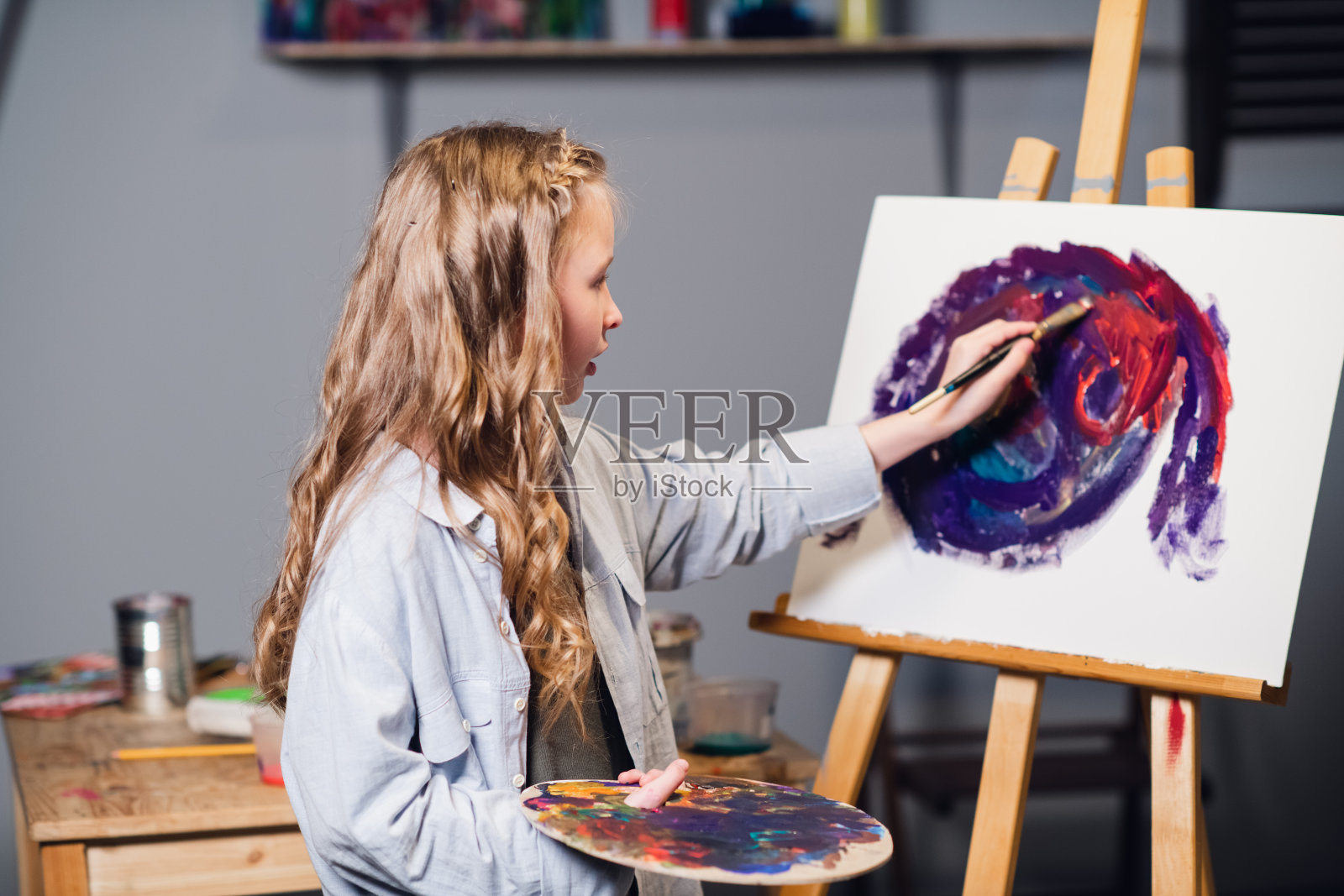 在艺术学校的第一节课上，一个小女孩学习画画，并在帆布上画了她的第一张油画照片摄影图片