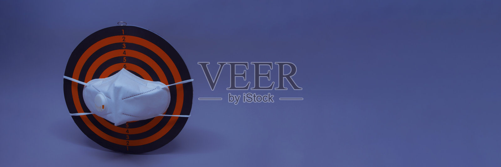 新冠肺炎医用口罩在飞镖的背景下。口罩模式的概念和预防大流行的健康保护。照片摄影图片