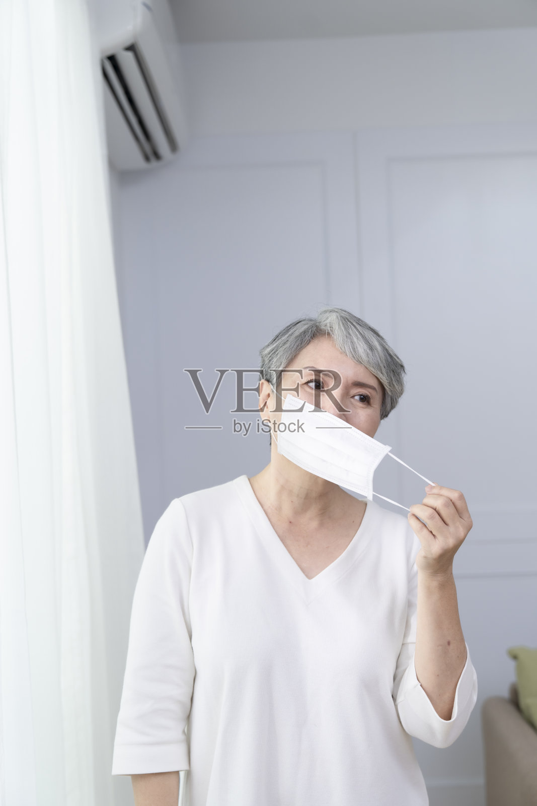 老年妇女拿起口罩，戴上口罩照片摄影图片