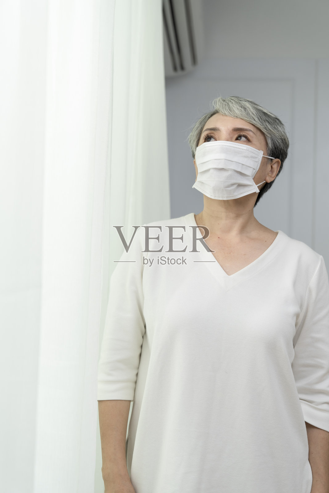 老年妇女拿起口罩，戴上口罩照片摄影图片