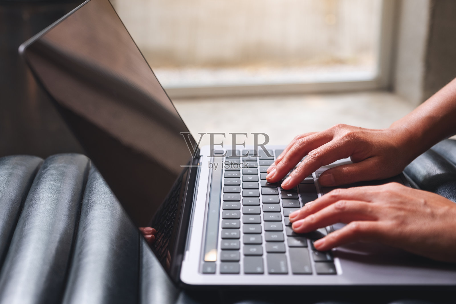 一个工作的女人，在桌上的笔记本电脑键盘上打字照片摄影图片