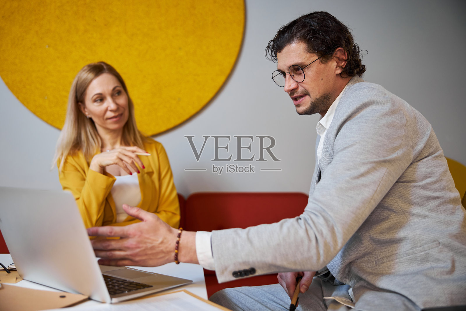 愉快的办公室职员在谈话中指着屏幕照片摄影图片