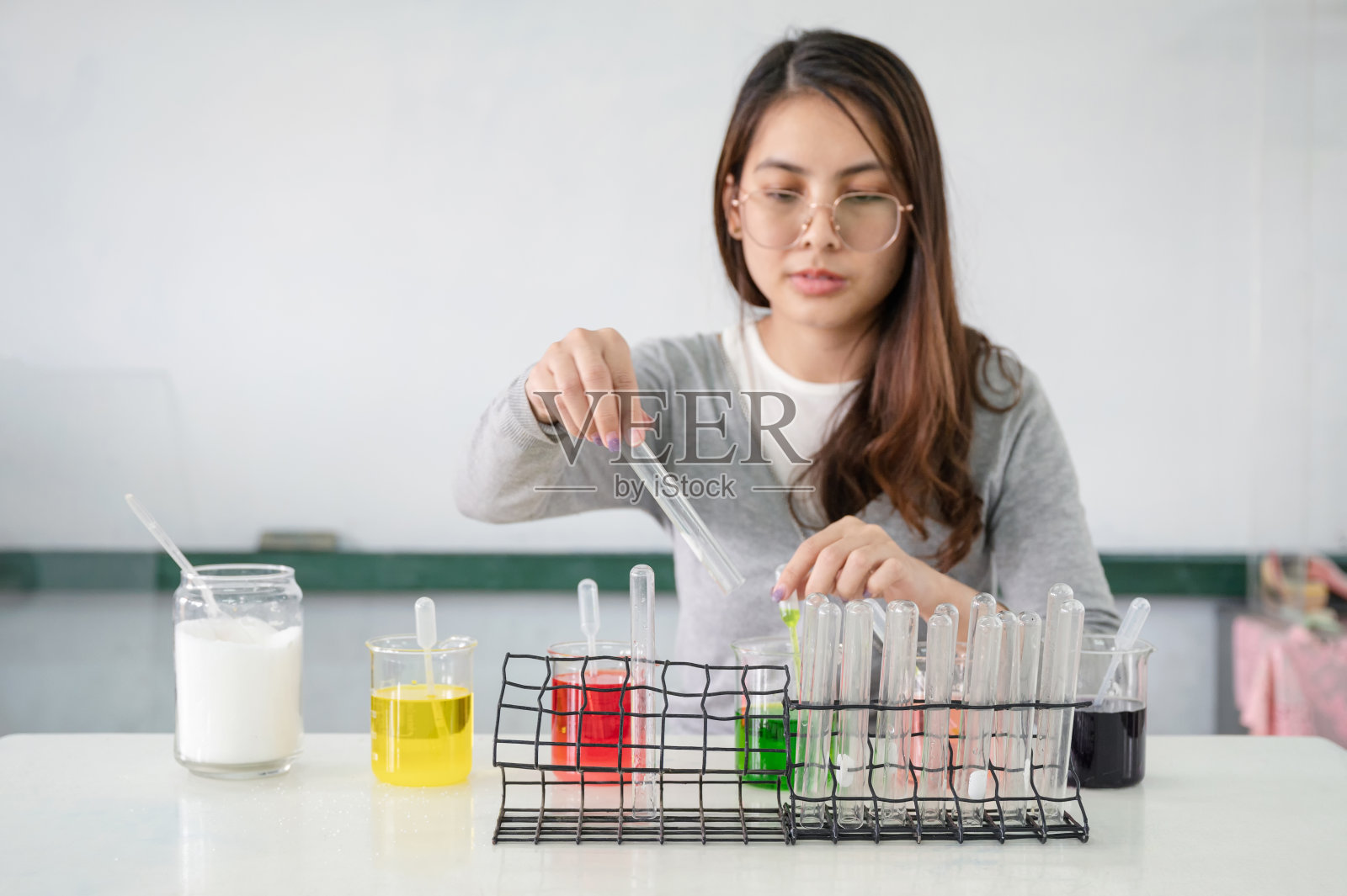 科学课上，实验室里的亚裔女学生在试管、彩色烧杯中制作分析和混合液体照片摄影图片