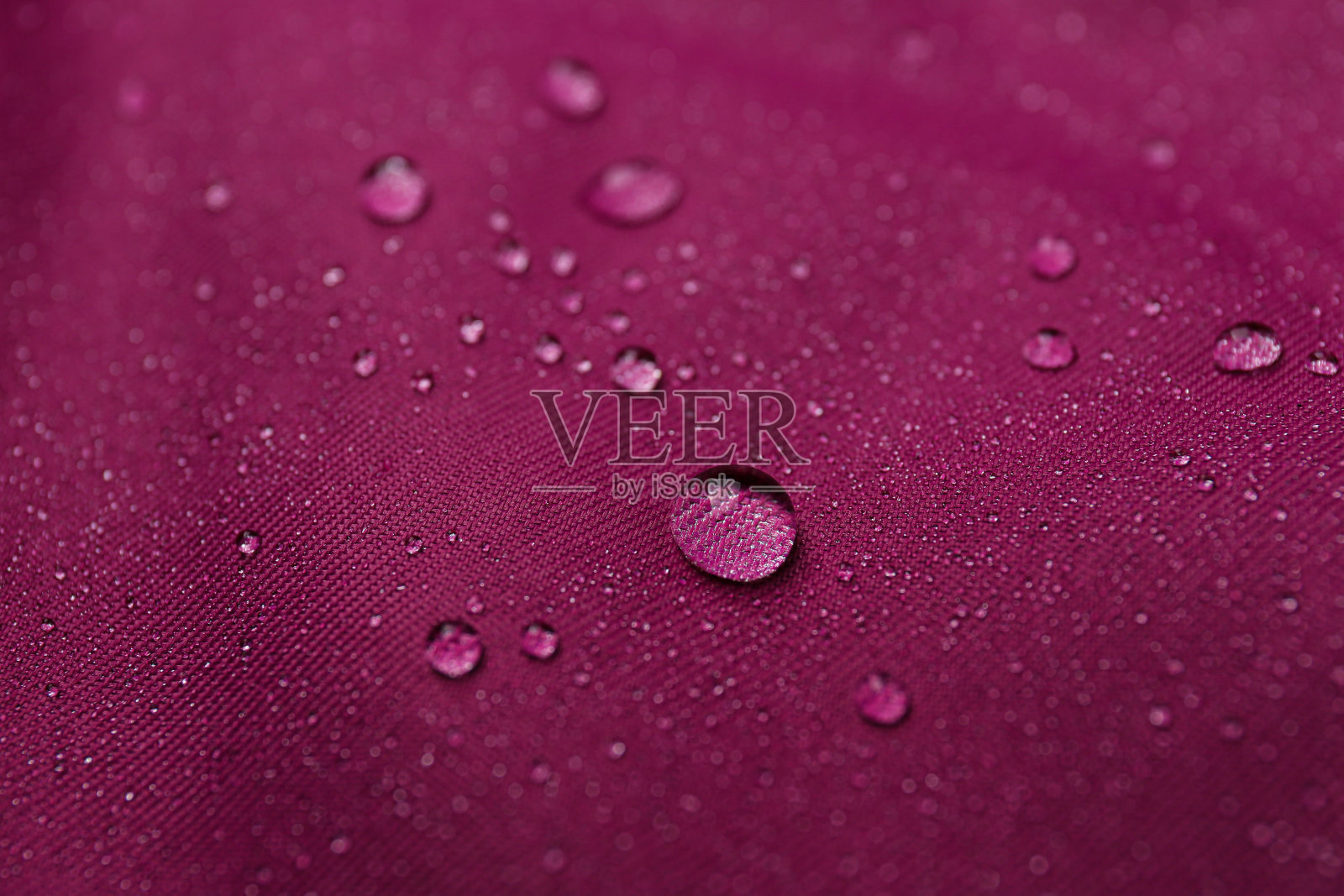 深粉色防水织物与水滴作为背景，特写照片摄影图片