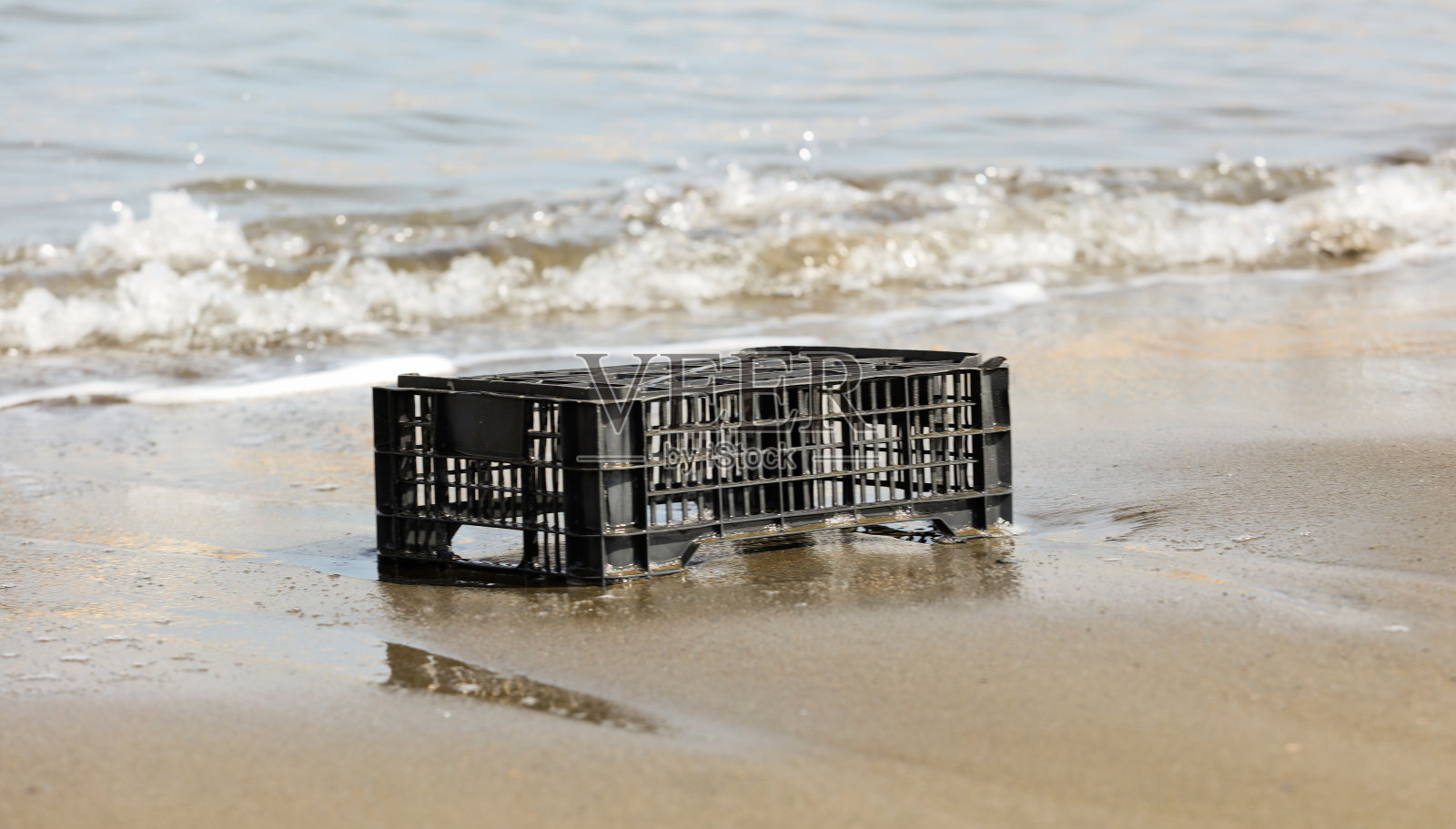 黑色塑料盒被扔到岸边，环境污染，照片摄影图片