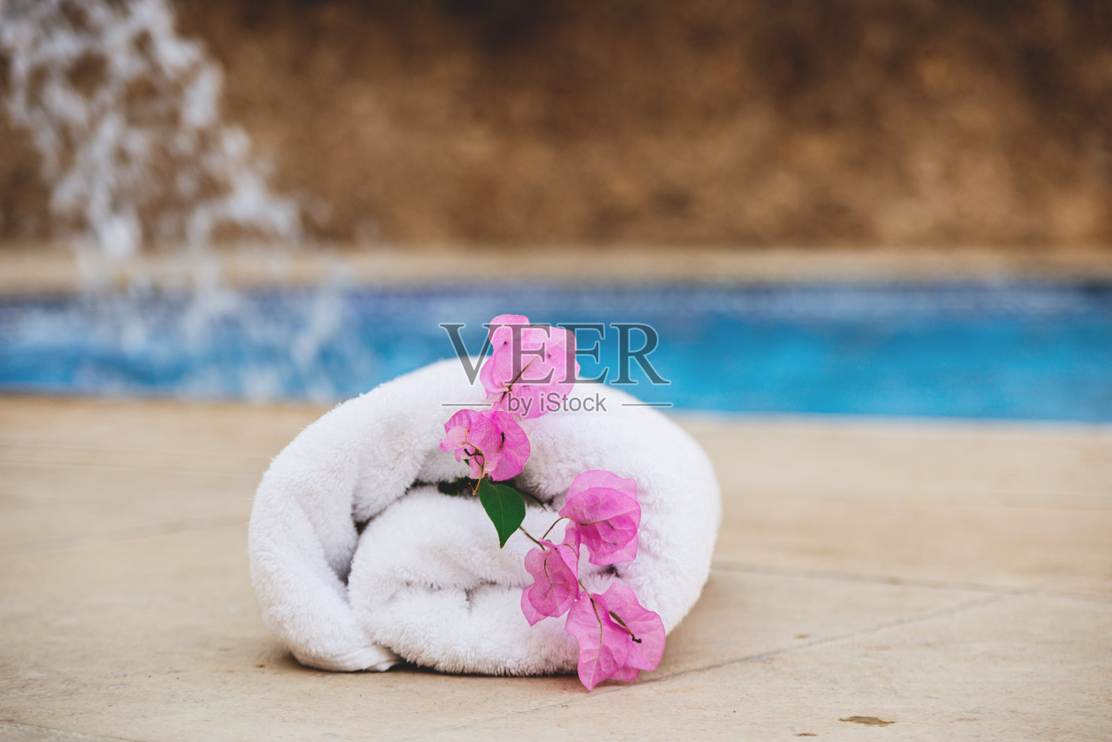 白色毛巾与粉红色的花附近温泉池在度假酒店照片摄影图片