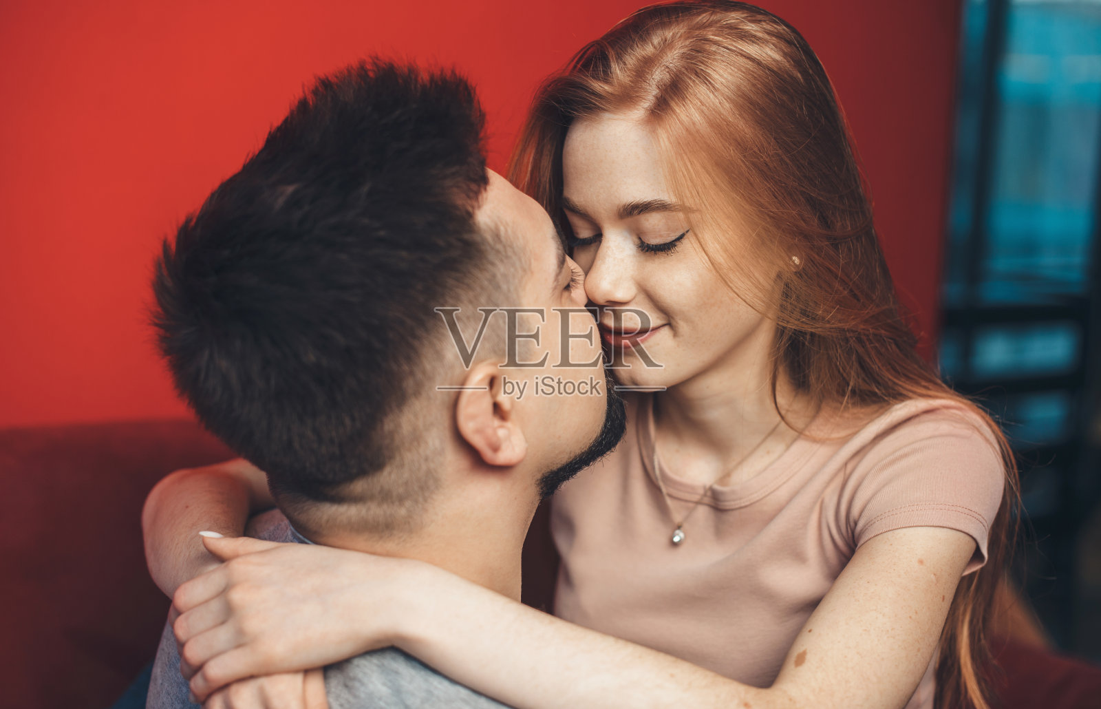 姜女人拥抱她的爱人和亲吻，而躺在沙发上照片摄影图片