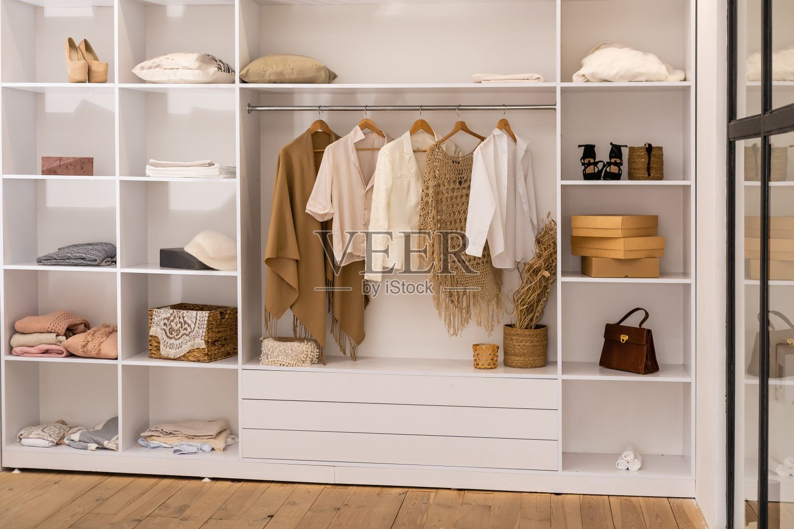 衣服挂在有箱子的白色衣柜的栏杆上照片摄影图片