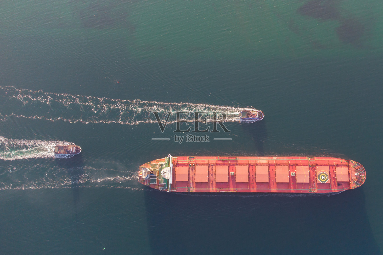 干货船在拖船的帮助下进入港口。来自直升机的照片。鸟瞰图。照片摄影图片