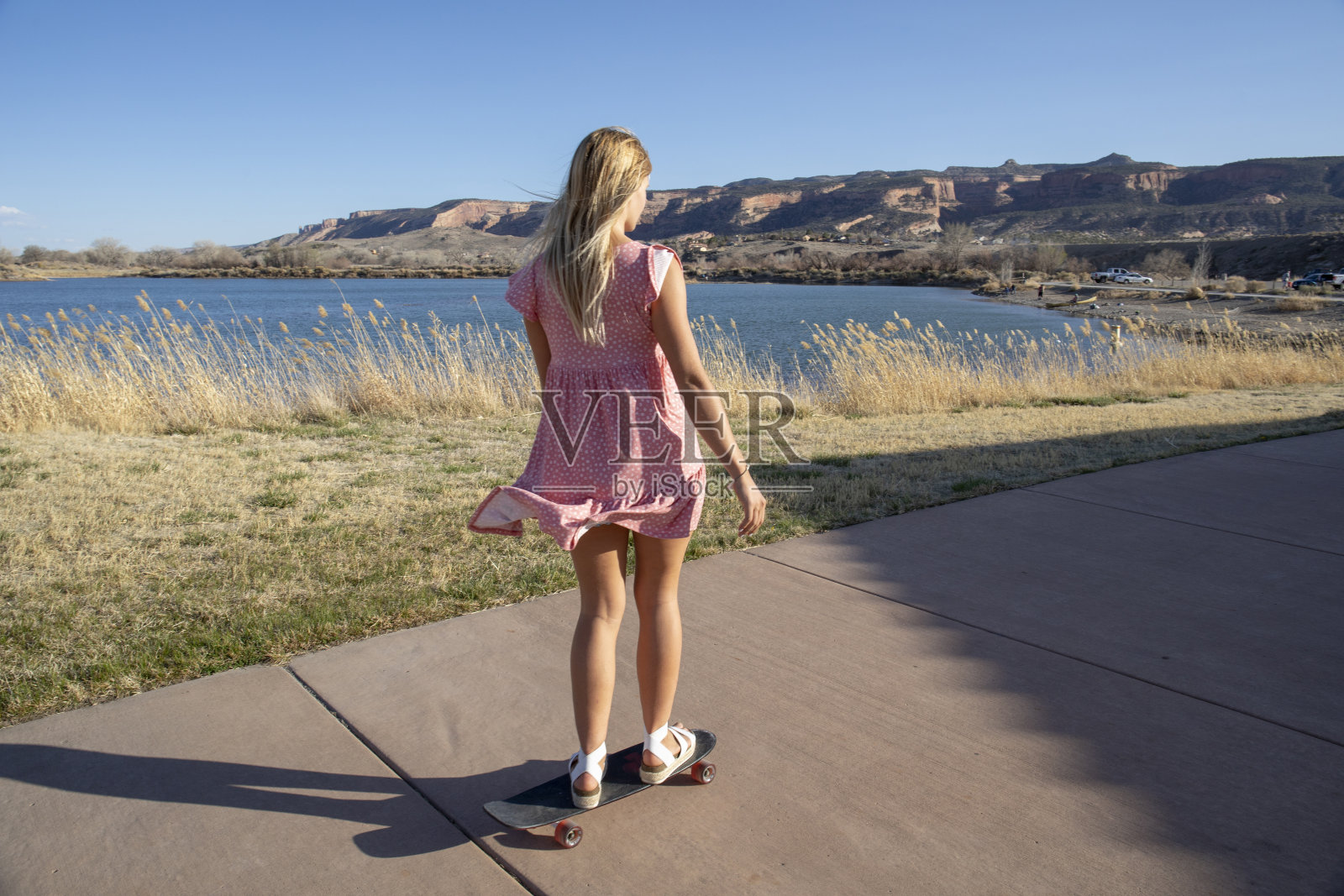 年轻女子早晨沿着湖岸玩滑板照片摄影图片