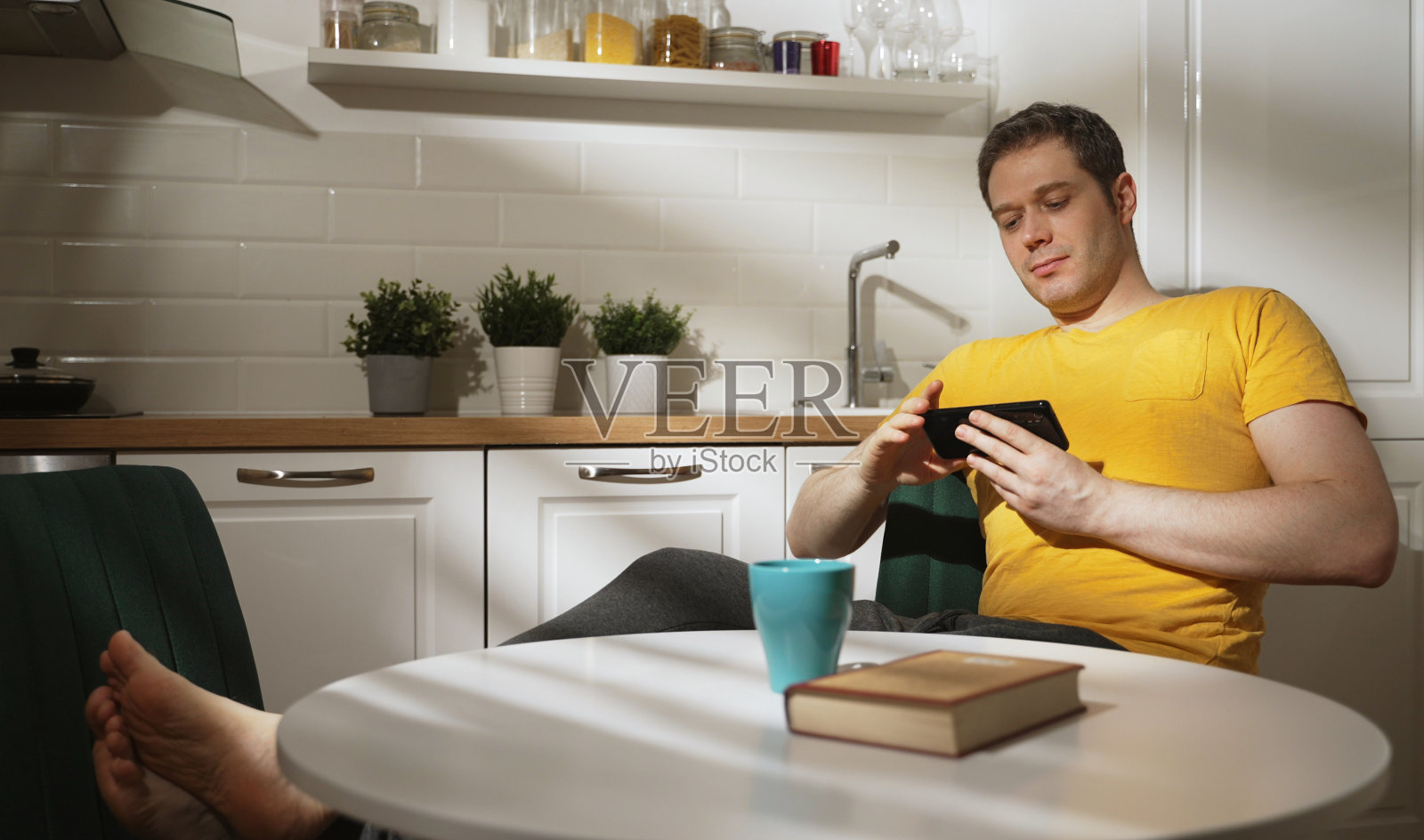 在厨房里用智能手机的男人。照片摄影图片