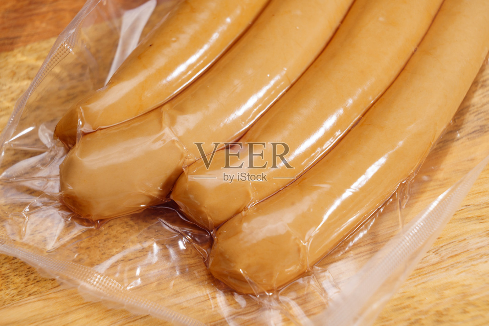 生香肠真空包装在木砧板上。肉类半成品。照片摄影图片