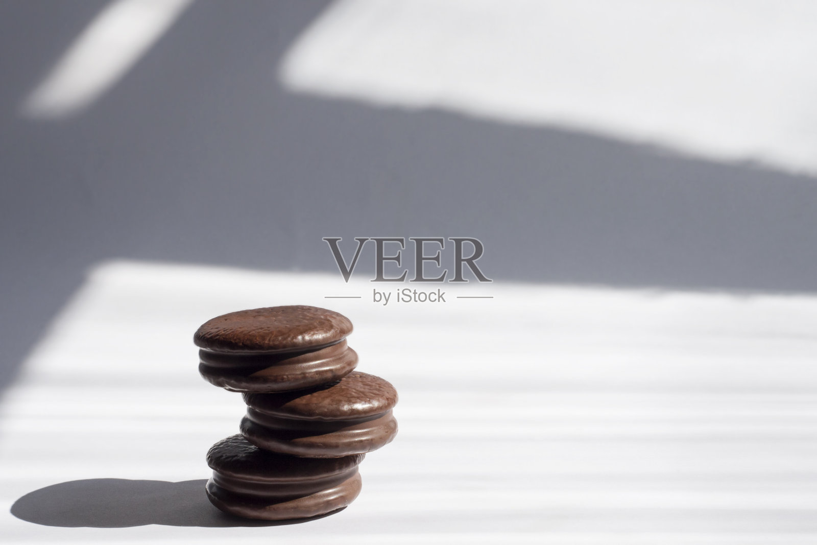 巧克力饼干堆在一个明亮的背景阴影和阳光。糖果的概念，文本的地方。照片摄影图片