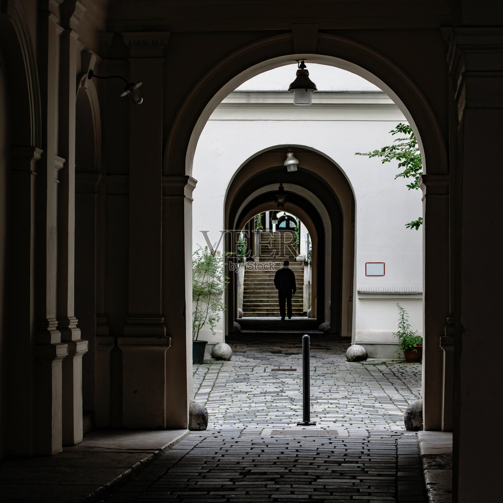 一个人穿过建筑物的通道照片摄影图片