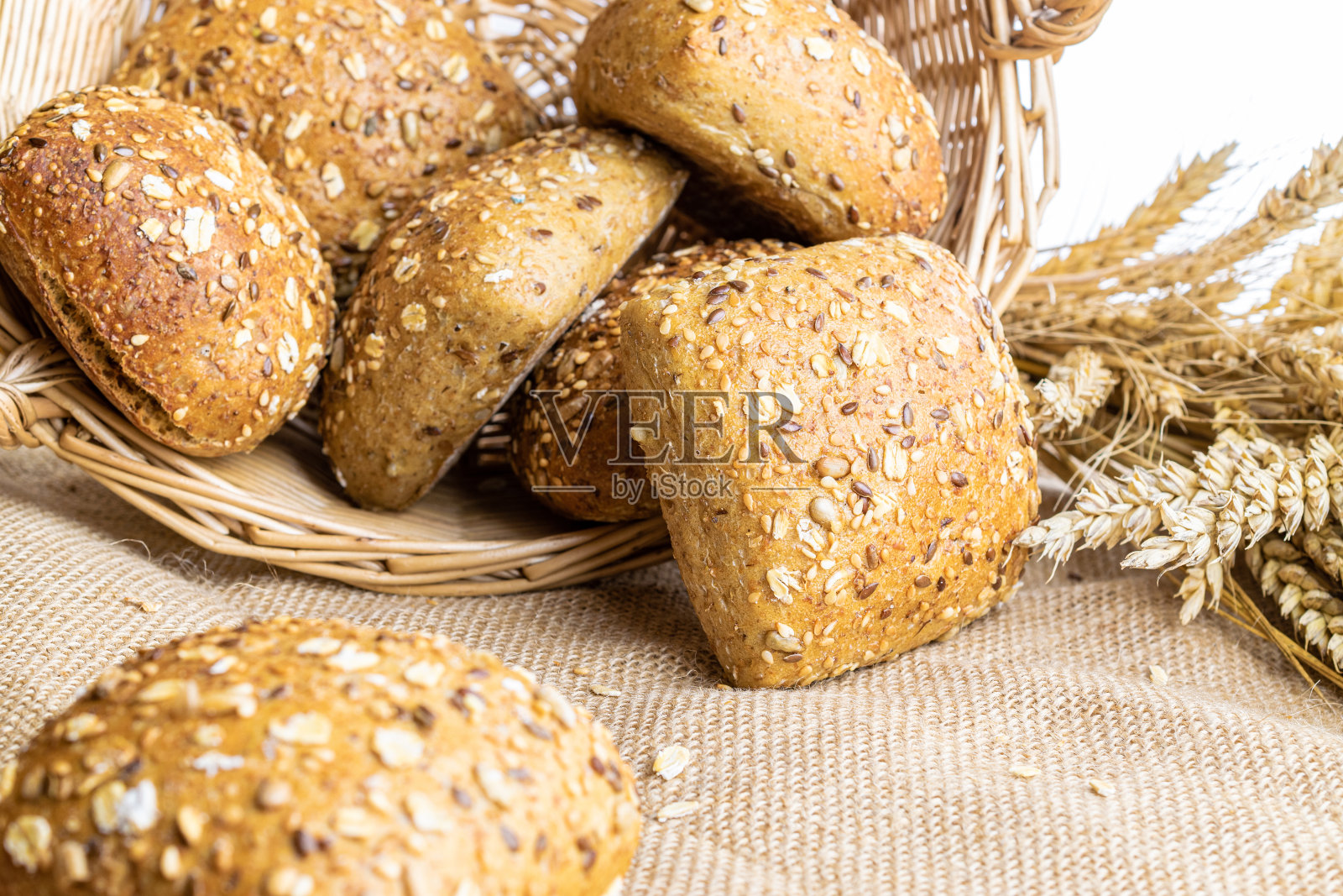 传统的面包。在亚麻质地的背景下，以小麦穗或穗状花序种植的乡村传统面包的新鲜面包。黑麦面包和硬面包。烘焙产品标签的设计元素。照片摄影图片