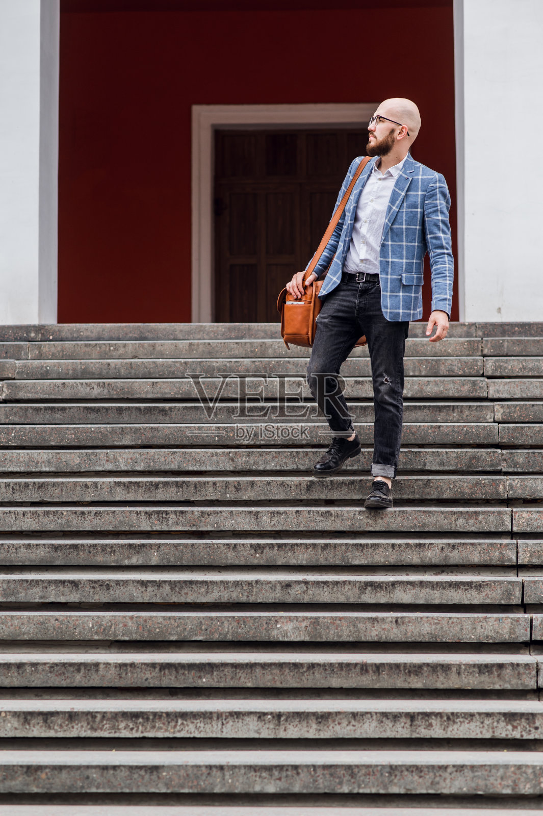 穿着蓝格子夹克的时髦年轻人走下楼梯照片摄影图片