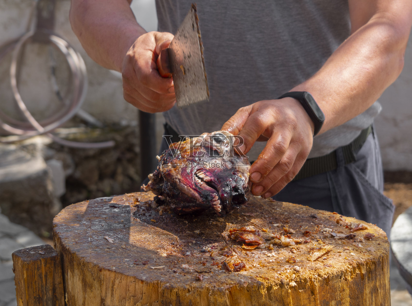 在希腊的埃维亚岛上，一名男子正在木头上用一把斧头切肉，这是复活节的传统食物——把山羊或羊羔放在叉上照片摄影图片